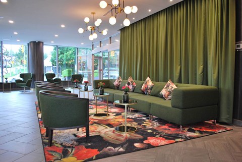 A living room with a green couch and a floral rug.