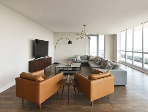 A living room with a brown sofa and a television on the wall.