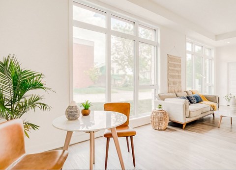 A living room with a white table and chairs, a couch, and a plant.