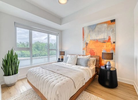 A bedroom with a large bed, a potted plant, and a painting on the wall. at Château golf, Gatineau Quebec