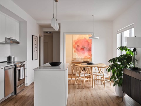 A modern kitchen with a white island and wooden chairs.