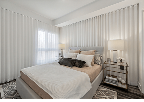 A bedroom with a large bed and a window with curtains.