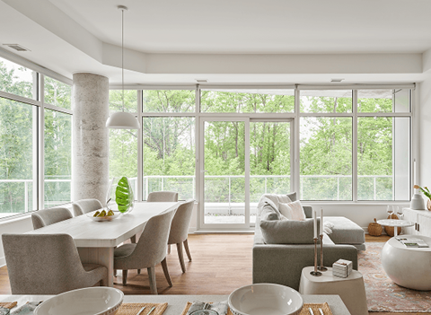 A modern dining room with a table set for two and a view of the trees outside at Petries Landing I Apartments , Ottawa, ON