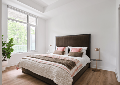 A bedroom with a large bed and a potted plant.