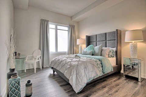 A bedroom with a large bed and a chair by the window.
