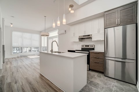 A modern kitchen with a stainless steel refrigerator and wooden floors.