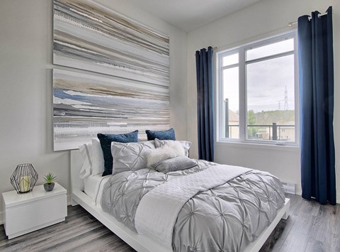 A bedroom with a large bed and a large picture on the wall.