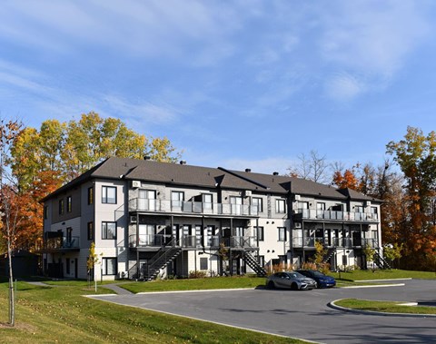 A large white building with a black roof and a balcony on the second floor.