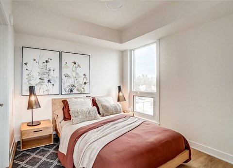 A bedroom with a large bed and two lamps.