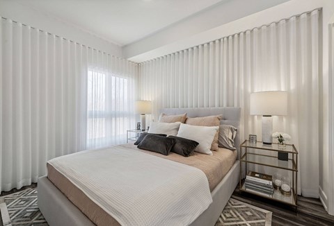 A bedroom with a large bed and a window with curtains.