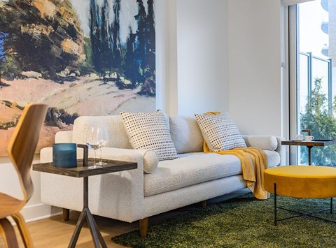 A living room with a white couch and a painting on the wall.