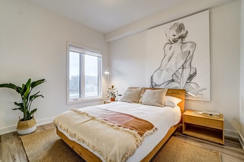 A bedroom with a large bed and a large drawing of a woman on the wall.
