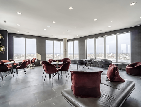 A modern living room with red chairs and a black couch.