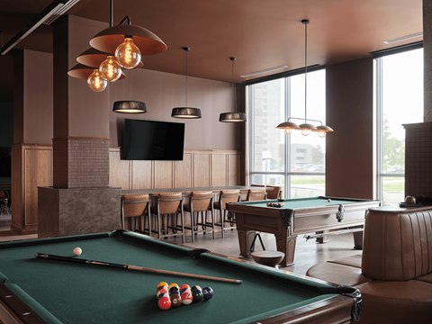 A pool table with a green felt cloth and a television mounted on the wall at The Dale Apartments , Ontario, K1Y 4Y5