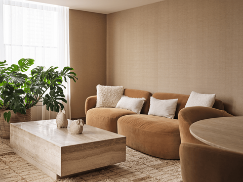A living room with a brown sofa, a coffee table, and a potted plant.