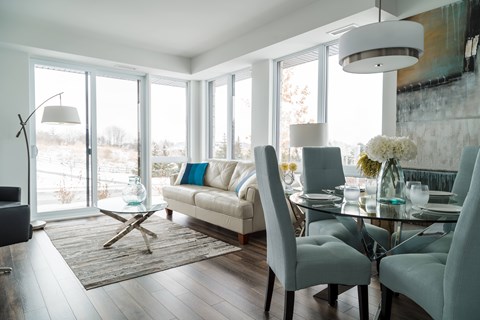 A modern dining room with a glass table and grey chairs.