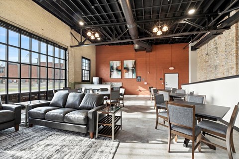 A living room with a black leather couch and a grey rug.