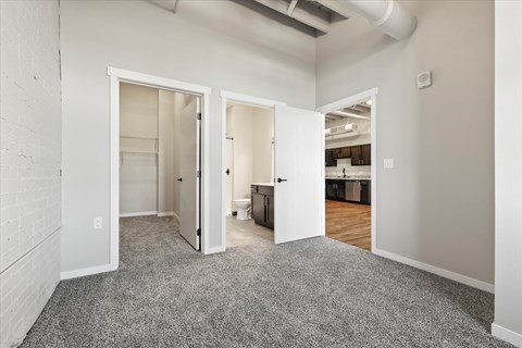 A room with a grey carpet and white walls with a doorway leading to another room.