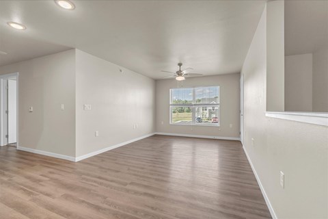 A spacious room with wooden flooring and a ceiling fan.