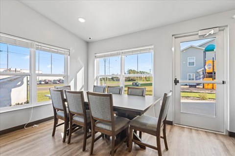 A dining room with a table and chairs and a view of the outside.
