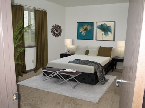 A bedroom with a bed, two lamps, and two pictures on the wall.