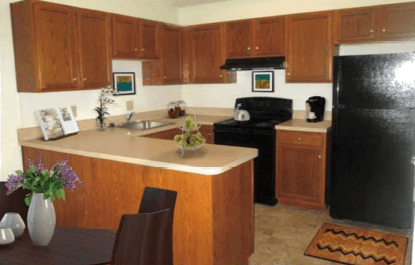 A kitchen with wooden cabinets and a black refrigerator.
