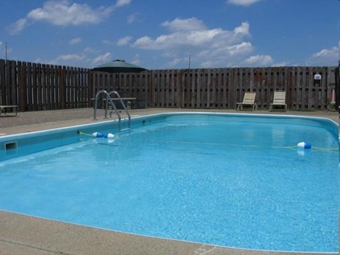 A small pool with a ladder and a green umbrella.