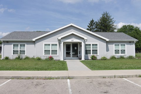 A small building with a grey roof and a white door.