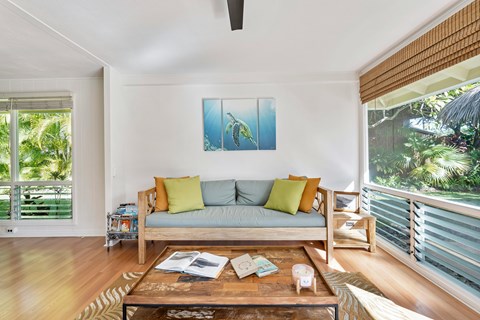 A living room with a couch, a coffee table, and a painting on the wall.