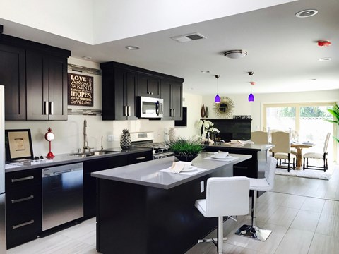 A modern kitchen with black cabinets and a white island.