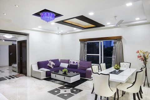 A modern living room with a purple couch and a white dining table.