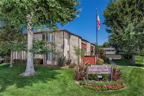A building with a sign that says "Brighton Park Apartments" in front of it.