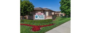 A sign for Foothill Village Apartments is in front of a building.