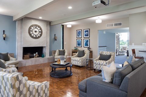 A living room with a fireplace and a large clock on the wall.