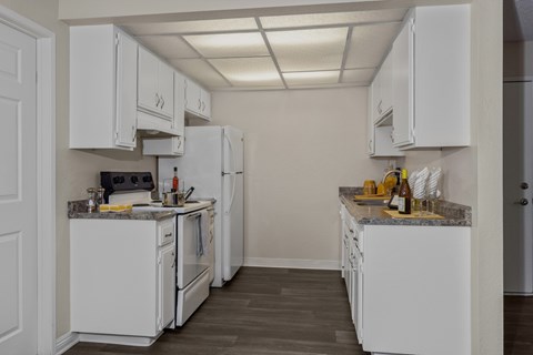 A kitchen with white appliances and cabinets.