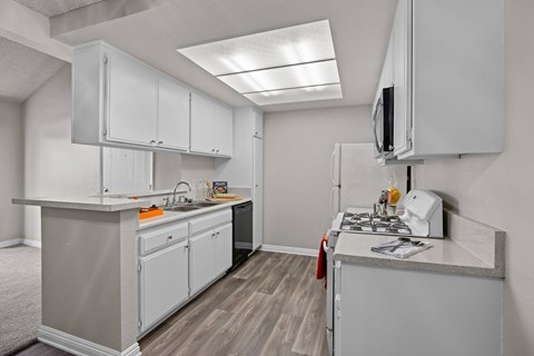 A kitchen with white cabinets and a grey counter top.