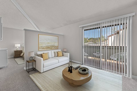 A living room with a white couch and a painting on the wall.