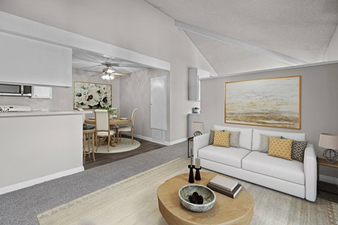 A modern living room with a white couch and a painting on the wall.