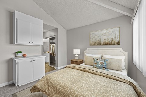 A bedroom with a bed, nightstand, and a painting on the wall.