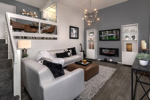 A modern living room with a grey couch and a fireplace.