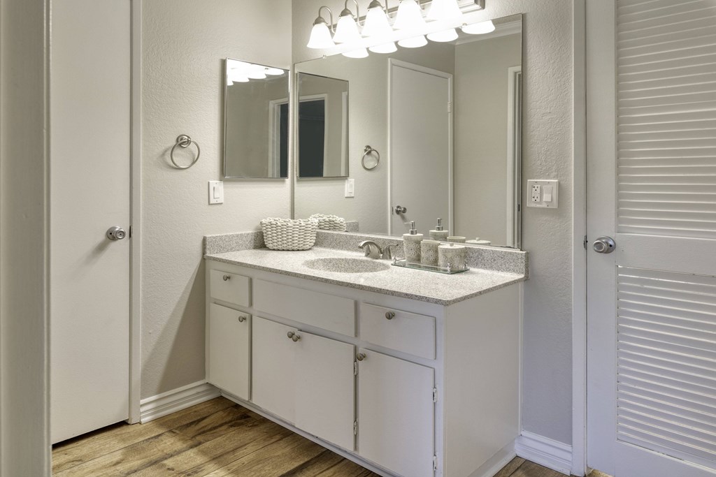 A white bathroom vanity with a mirror and lights above it.