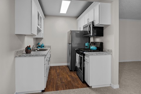 A kitchen with white cabinets and a black refrigerator.