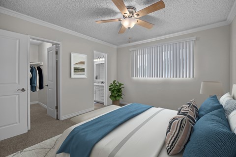 A bedroom with a bed, pillows, a ceiling fan, and a window with blinds.