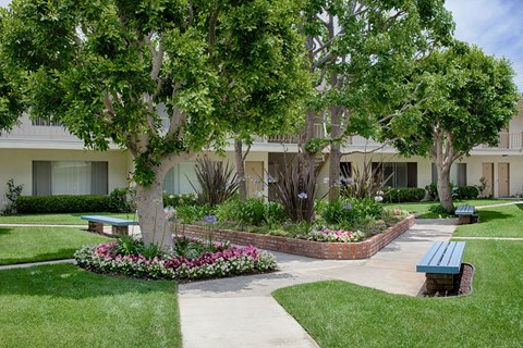A walkway through the courtyard with a flowerbed and bench on the sides.