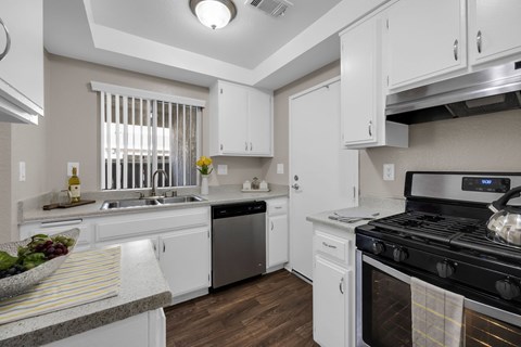 A modern kitchen with white cabinets and a black stove top.
