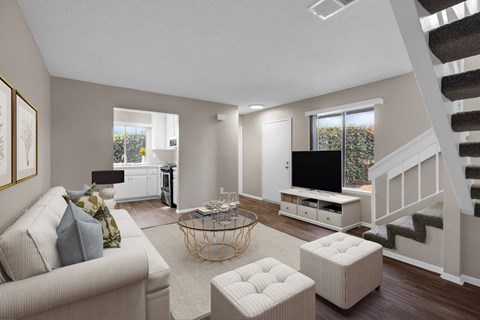 A living room with a couch, a coffee table, and a staircase.