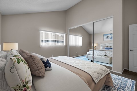 A bedroom with a large bed and a mirrored closet door.