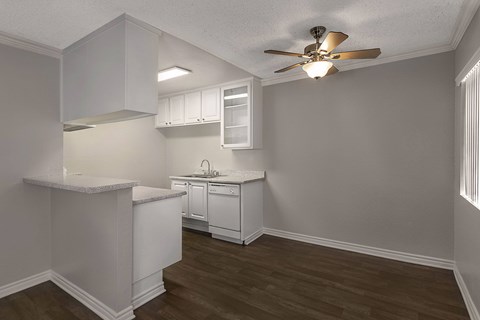 A kitchen with white cabinets and a ceiling fan.
