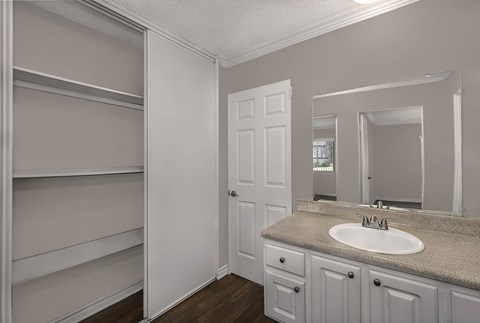 A bathroom with a sink, mirror, and shelves.