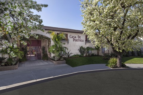 A "Casa de Portola" sign on a building with trees in front.
